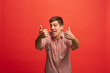 Image showing The happy businessman standing and smiling against red background.