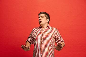 Image showing Beautiful male half-length portrait isolated on red studio backgroud. The young emotional surprised man