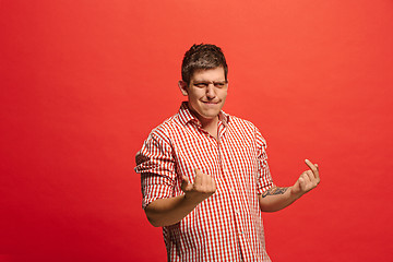 Image showing Beautiful male half-length portrait isolated on red studio backgroud. The young emotional surprised man