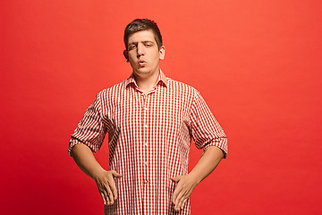 Image showing Beautiful male half-length portrait isolated on red studio backgroud. The young emotional surprised man