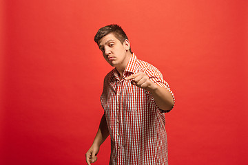 Image showing Beautiful male half-length portrait isolated on red studio backgroud. The young emotional surprised man