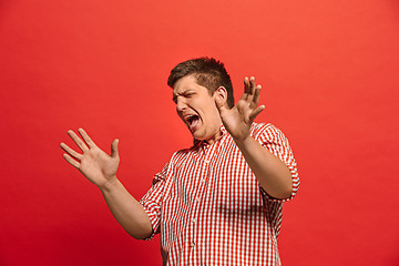 Image showing Beautiful male half-length portrait isolated on red studio backgroud. The young emotional surprised man