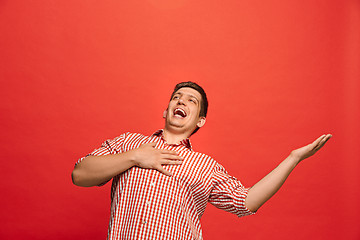 Image showing The happy business man standing and smiling against red background.