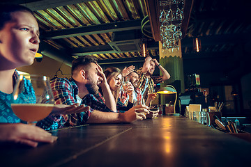 Image showing Upset male and female friends watching sport game or football match and drinking beer at bar or pub.