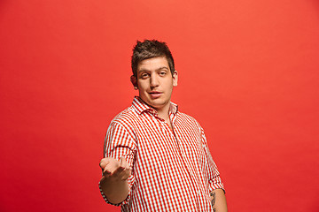 Image showing Beautiful male half-length portrait isolated on red studio backgroud. The young emotional surprised man
