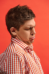 Image showing Doubtful pensive man with thoughtful expression making choice against red background