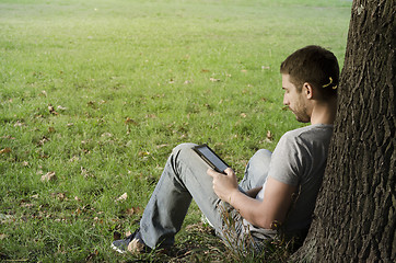 Image showing 	Young man reading e-book