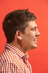 Image showing The happy business man standing and smiling against red background.