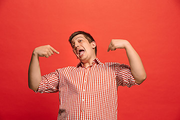 Image showing The happy business man standing and smiling against red background.