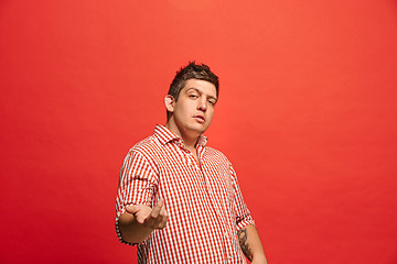 Image showing Beautiful male half-length portrait isolated on red studio backgroud. The young emotional surprised man