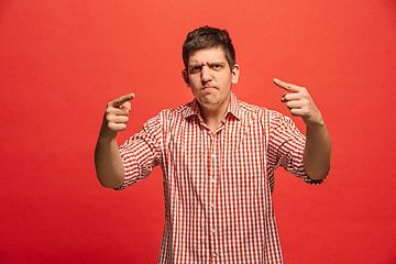 Image showing The young emotional angry man screaming on red studio background