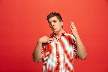 Image showing Beautiful male half-length portrait isolated on red studio backgroud. The young emotional surprised man