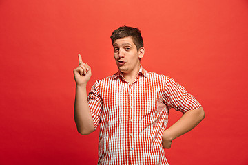 Image showing Beautiful male half-length portrait isolated on red studio backgroud. The young emotional surprised man