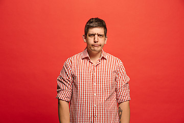 Image showing Beautiful male half-length portrait isolated on red studio backgroud. The young emotional surprised man