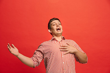 Image showing The happy business man standing and smiling against red background.