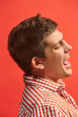 Image showing The happy business man standing and smiling against red background.