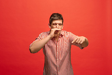 Image showing The young man whispering a secret behind her hand over red background