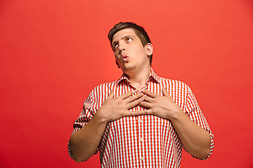 Image showing The happy business man standing and smiling against red background.