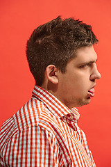 Image showing Doubtful pensive man with thoughtful expression making choice against red background