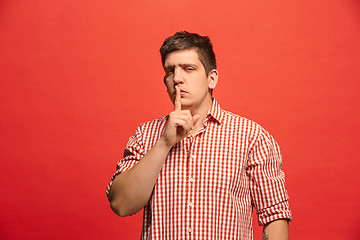 Image showing The young man whispering a secret behind her hand over green background