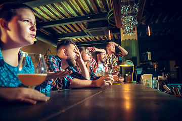 Image showing Upset male and female friends watching sport game or football match and drinking beer at bar or pub.