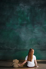 Image showing Little girl with teddy bear sitting on floor in empty room. Autism concept