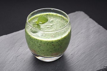 Image showing Green smoothie made from spinach, kale, avocado and banana garnished with a mint leaf.