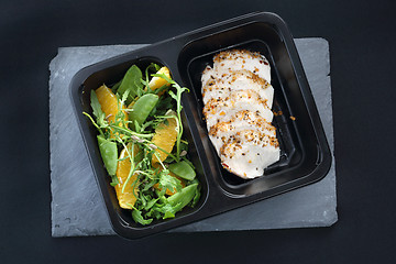 Image showing Balanced box diet, dinner dish. Poultry fillet on a salad with sugar peas and oranges on a black plate.