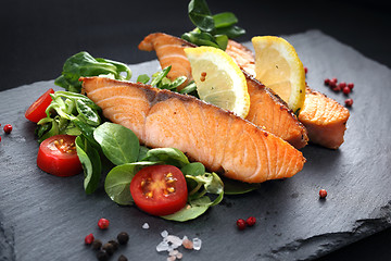 Image showing Pieces of baked salmon on lettuce