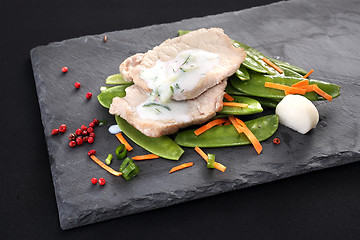 Image showing Cooked meat on a sweet pea salad served with white yoghurt sauce.