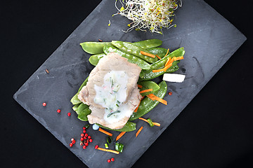 Image showing Cooked meat on a sweet pea salad served with white yoghurt sauce.