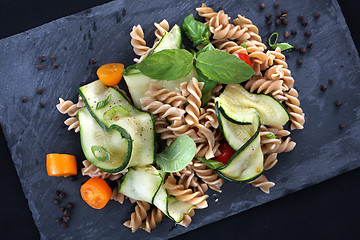 Image showing Macaroni salad. Spiral pasta with vegetables. on a black plate.