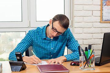 Image showing An office worker writes a statement at the table