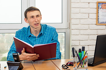 Image showing Office worker polls the visitor and scrolls through the folder with documents