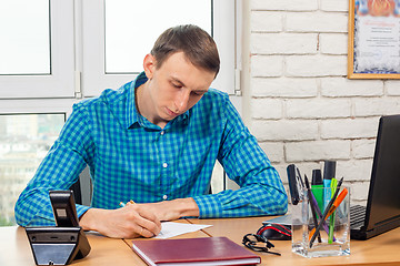 Image showing Young office specialist at the table writes a statement