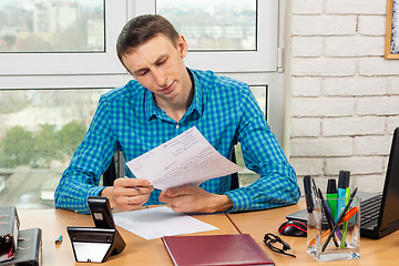 Image showing The supervisor carefully reads the visitor\'s application