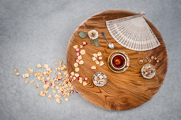 Image showing Vintage wooden table with tea and rose petals