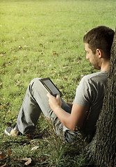 Image showing Young man reading e-book