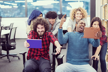 Image showing multiethnics business team racing on office chairs