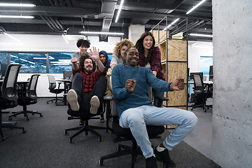 Image showing multiethnics business team racing on office chairs