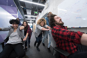 Image showing multiethnics business team racing on office chairs