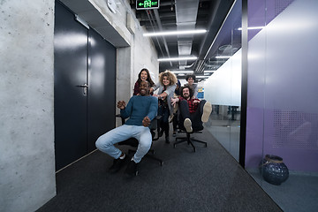 Image showing multiethnics business team racing on office chairs