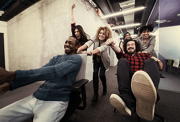 Image showing multiethnics business team racing on office chairs