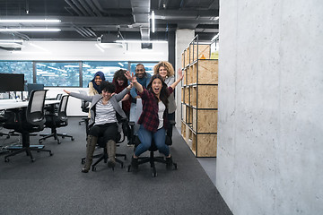 Image showing multiethnics business team racing on office chairs