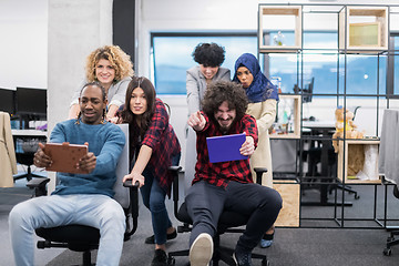 Image showing multiethnics business team racing on office chairs