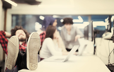 Image showing software developer resting with legs on desk