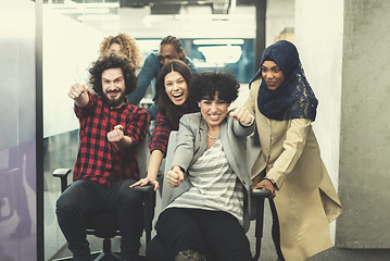 Image showing multiethnics business team racing on office chairs