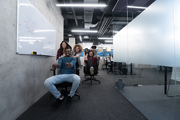 Image showing multiethnics business team racing on office chairs