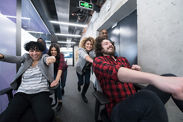 Image showing multiethnics business team racing on office chairs