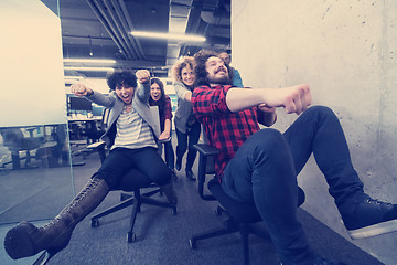 Image showing multiethnics business team racing on office chairs